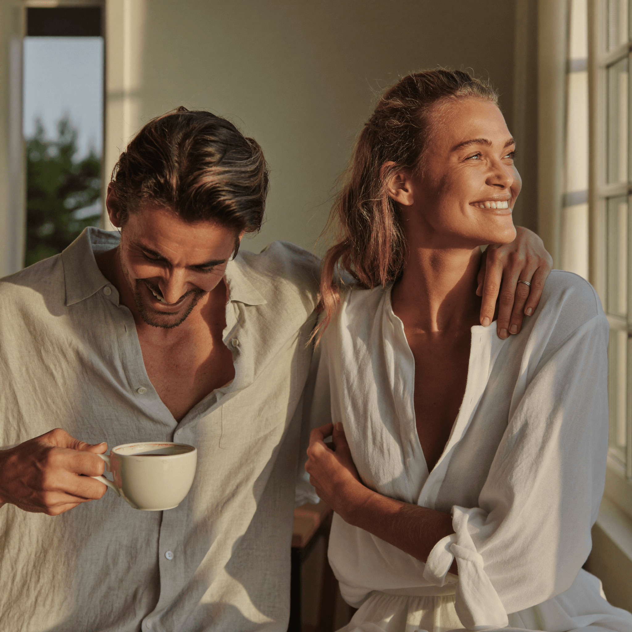 An Australian man in a quiet sunlit home setting holding a coffee, considered expression