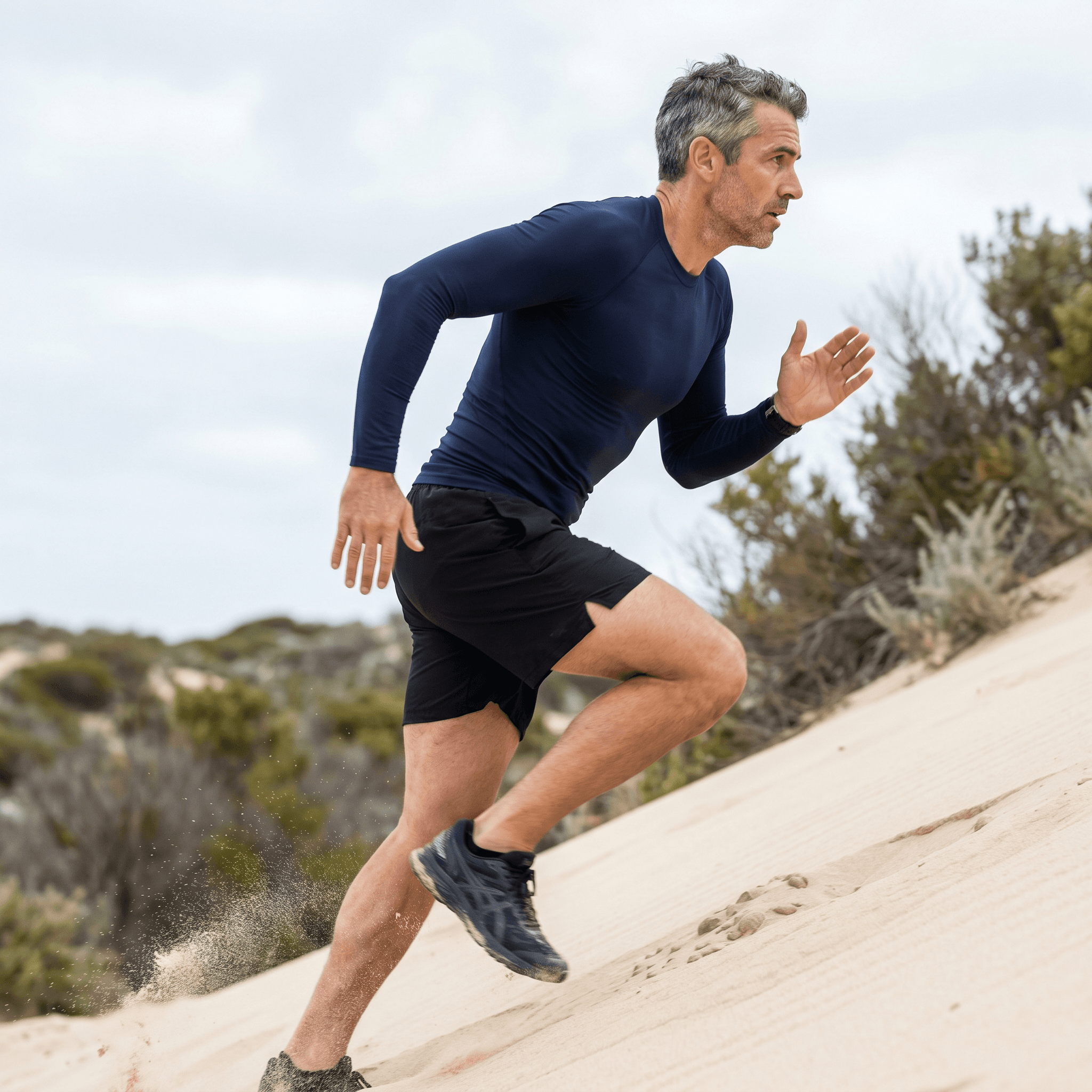 Australian man sprinting up a coastal sand dune